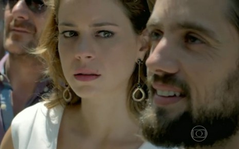 Cristina (Leandra Leal) está em pé ao lado de Vicente (Rafael Cardoso) em praça em cena de Império