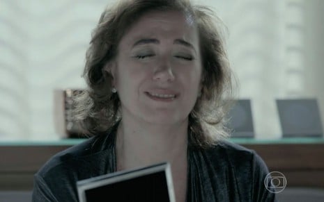 A atriz Lilia Cabral chora segurando um porta-retrato como a personagem Maria Marta em cena da novela Império, da Globo