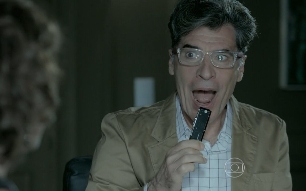 Paulo Betti grava com óculos de grau, blazer bege e expressão de surpresa como Téo Pereira de Império