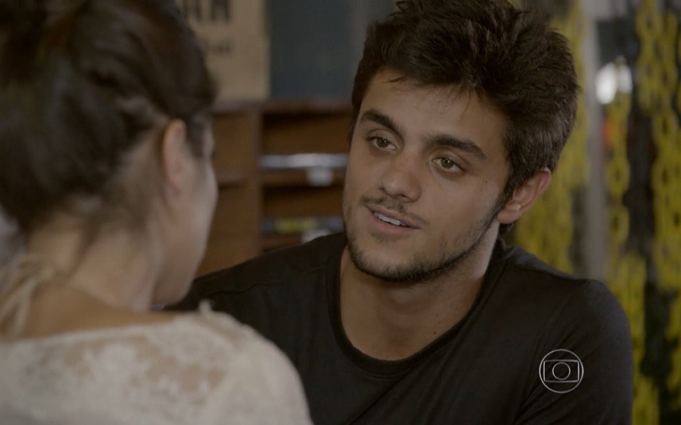 Felipe Simas grava de camiseta preta olhando para Anaju Dorigon, de costas na foto, como Cobra e Jade de Malhação