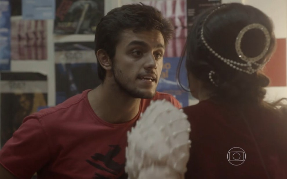 Felipe Simas grava de camiseta vermelha e expressão de raiva olhando para Anaju Dorigon, de costas, como Cobra e Jade