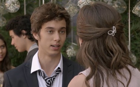 Guilherme Hamacek grava cena com expressão séria para Bruna Hamú, que aparece de costas na imagem, como João e Bianca