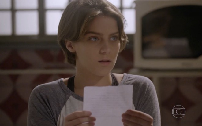 Isabella Santoni grava cena segurando papel, com expressão tensa para Arthur Aguiar que não aparece na imagem, como Karina e Duca em Malhação Sonhos, da Globo