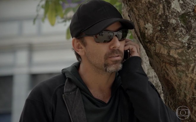 Marcelo Faria grava cena com expressão séria ao telefone, de óculos escuros, como Lobão de Malhação