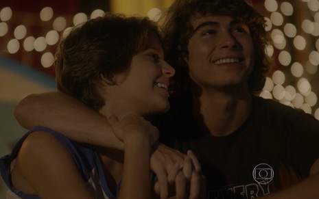 Isabella Santoni grava ao lado de Rafael Vitti, ambos sorridentes em cenário iluminado como Karina e Pedro de Malhação