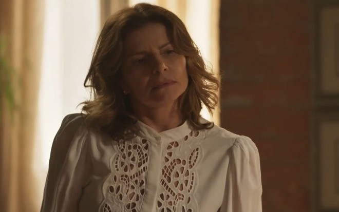 Debora Bloch caracterizada como Deodora; ela usa uma camisa branca de renda e tem o semblante sério em cena de Mar do Sertão