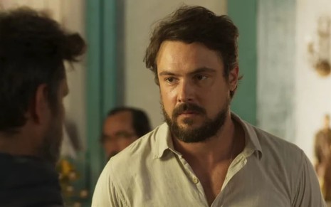 Sergio Guizé em cena de Mar do Sertão; ator usa uma camisa branca e tem o semblante sério