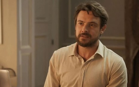 Sergio Guizé em cena de Mar do Sertão; ator usa uma camisa branca e sorri para a câmera