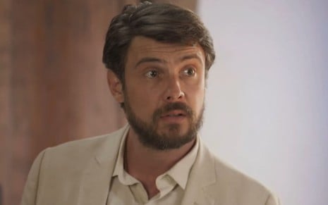 Sergio Guizé, caracterizado como Zé Paulino, usa uma camisa social e tem os cabelos arrumados; o ator tem o semblante sério em cena de Mar do Sertão