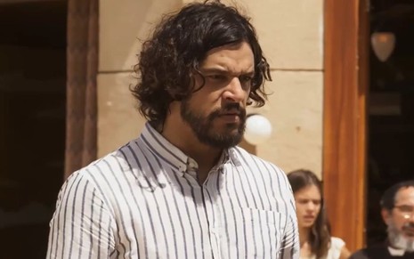 Pedro Lamin tem o semblante furioso em cena de Mar do Sertão; ele veste uma camisa social listrada e encara um ponto fixo com firmeza