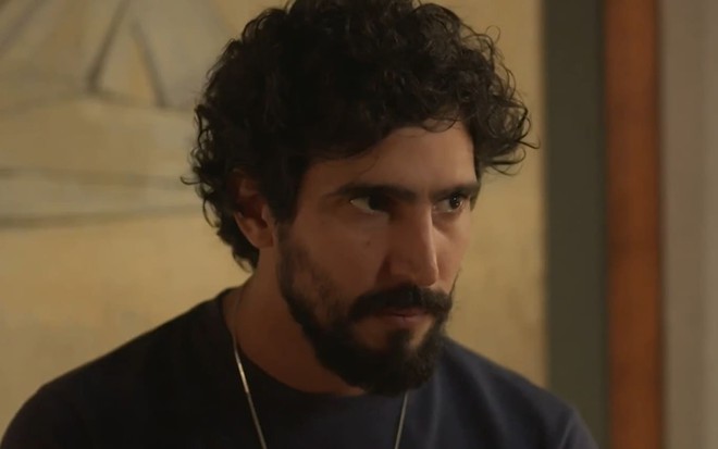 Renato Góes caracterizado como Tertulinho; ele tem os olhos arregalados e a expressão perturbada em cena de Mar do Sertão; ele segura uma arma e mira em Sergio Guizé --fora do quadro