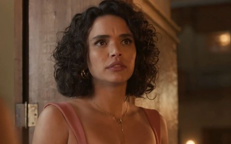 Giovana Cordeiro caracterizada como Xaviera; atriz usa um vestido vermelho e tem a expressão abalada em cena de Mar do Sertão