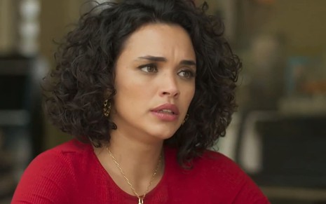 Giovana Cordeiro caracterizada como Xaviera; atriz usa um vestido vermelho e tem a expressão debochada em cena de Mar do Sertão