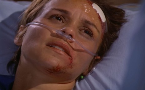 Giulia Gam caracterizada como Heloisa; ela usa uma sonda nasogástrica e tem o rosto ensanguentado em cena de Mulheres Apaixonadas