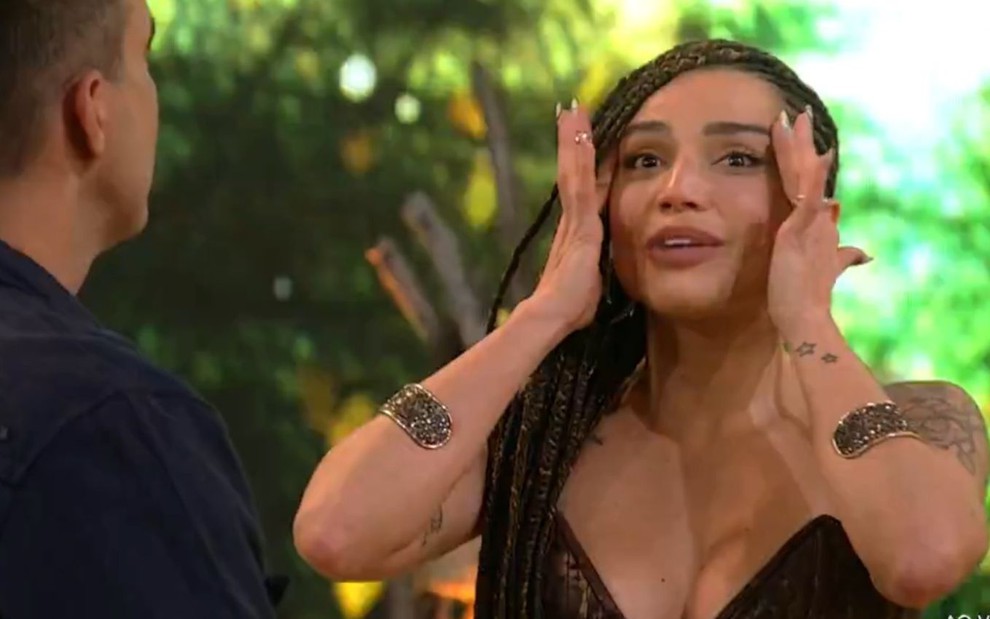 A participante do BBB18 e vencedora do No Limite 5 Paula Amorim segura o próprio rosto surpresa no programa exibido na terça-feira (20) na Globo