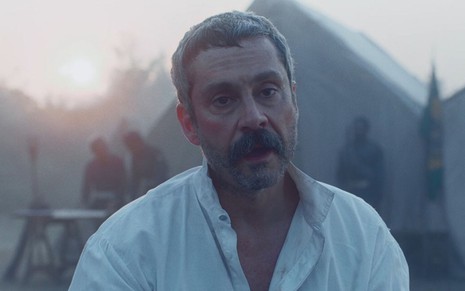 Alexandre Nero grava cena com expressão de sofrimento, como Tonico em Nos Tempos do Imperador, da Globo