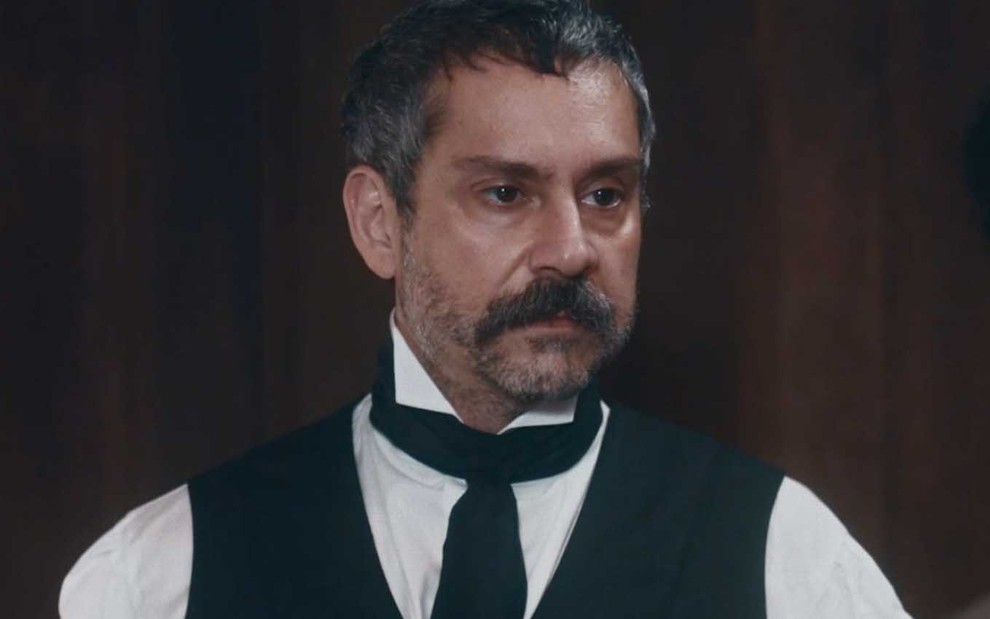 Tonico (Alexandre Nero) está em pé em gabinete; ele aparenta estar com raiva em cena de Nos Tempos do Imperador