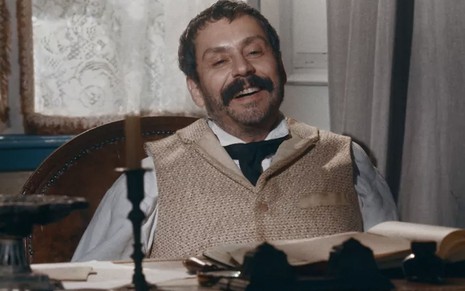 O ator Alexandre Nero como Tonico jogado em uma cadeira no seu gabinete na Câmara dos Deputados em cena de Nos Tempos do Imperador