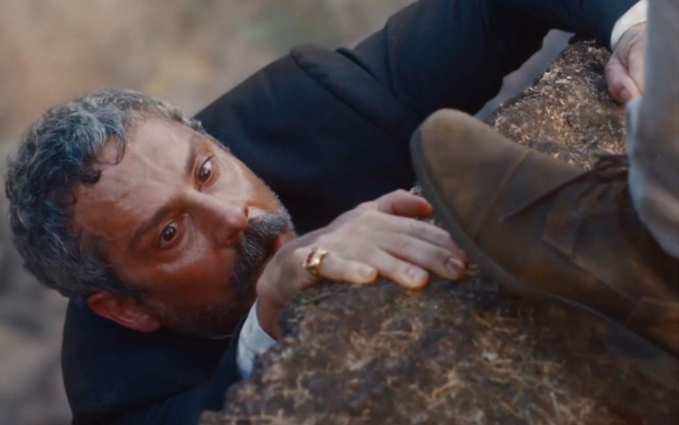 Tonico Rocha (Alexandre Nero) está com as mãos em pedra em precipício em cena de Nos Tempos do Imperador