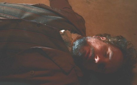 Quinzinho (Augusto Madeira) está deitado desmaiado no chão em cena de Nos Tempos do Imperador