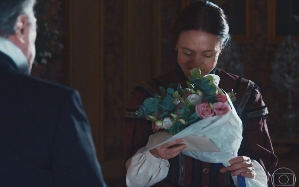 Celestina (Bel Kutner) segura e cheira buquê de flores na sala da Quinta da Boa Vista em Nos Tempos do Imperador