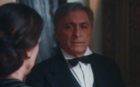 O ator Cássio Pandolfi com um smoking preto, com gravata borboleta preta, como o Nicolau em cena de Nos Tempos do Imperador