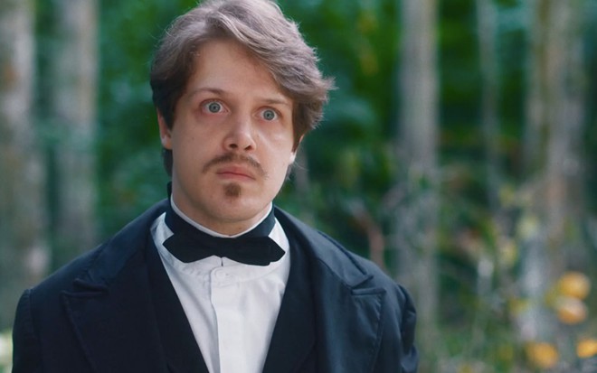 O ator Daniel Torres com expressão séria como o Gastão em um jardim em cena diurna de Nos Tempos do Imperador