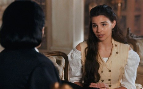 Pilar (Gabriela Medvedovski) está sentada na sala da Quinta da Boa Vista e conversa com Teresa Cristina (Leticia Sabatella), que está de costas, em cena de Nos Tempos do Imperador