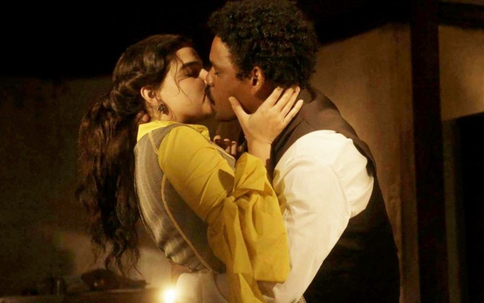 Pilar (Gabriela Medvedovski) e Samuel (Michel Gomes) se beijam na sala da casa do engenheiro em cena de Nos Tempos do Imperador