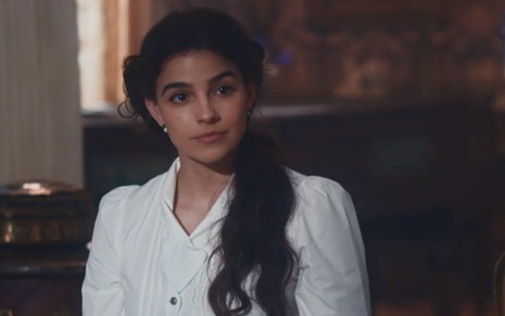 Pilar (Gabriela Medvedovksi) está sentada na sala da Quinta da Boa Vista em cena de Nos Tempos do Imperador