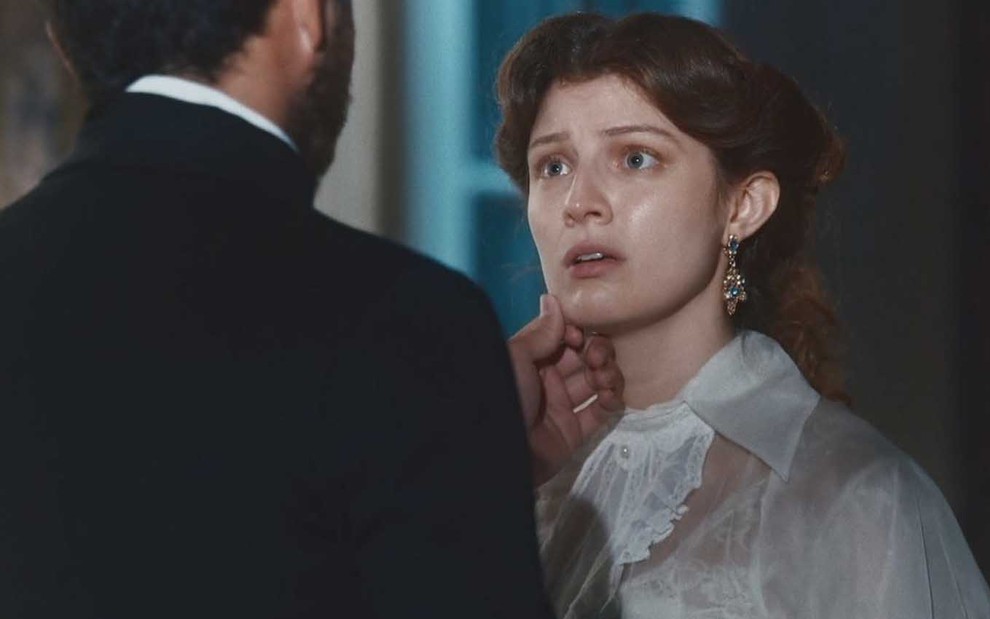 A atriz Giulia Gayoso conversa com um homem, de costas, com a expressão de surpresa e tristeza como a Isabel em cena de Nos Tempos do Imperador