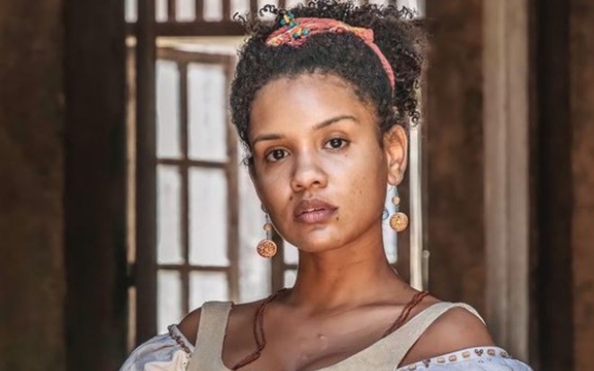 Atores Heslaine Vieira e Michel Gomes sorriem e posam para foto com figurinos da novela Nos Tempos do Imperador