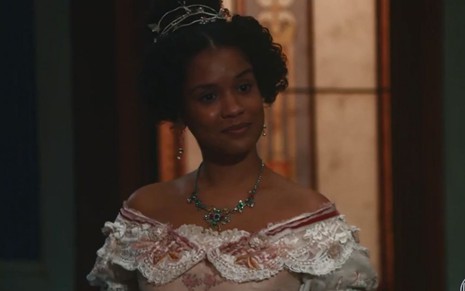 Zayla (Heslaine Vieira) veste roupa de gala está em pé na sala de Tonico (Alexandre Nero) em cena de Nos Tempos do Imperador