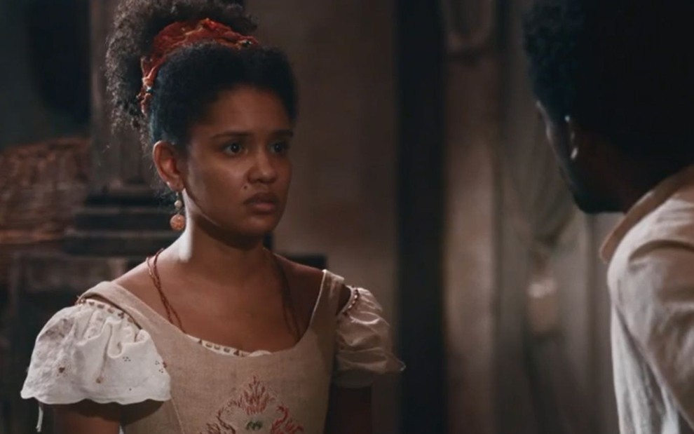 Zayla (Heslaine Vieira) conversa com Guebo (Maicon Rodrigues), que está de costas na foto, em cena de Nos Tempos do Imperador