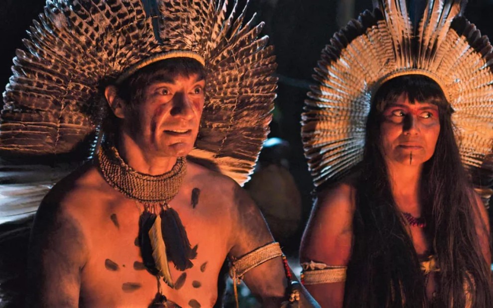 Clovys Torres e Valéria Alencar gravam pintados e vestidos como índios sentados no chão como Piatã e Jacira