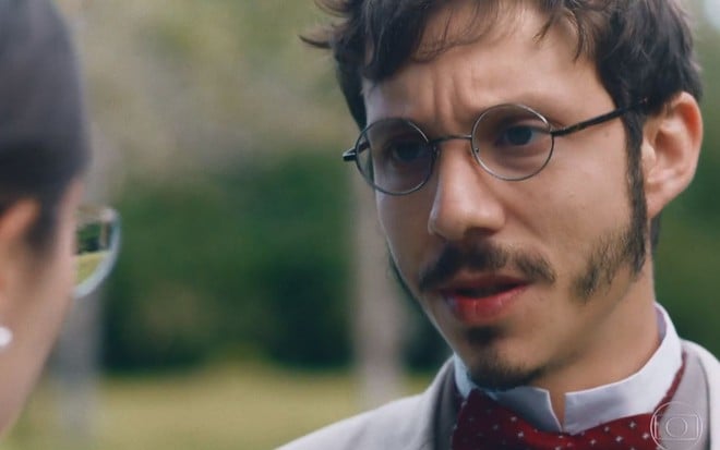 Nélio (João Pedro Zappa) conversa com Dolores (Daphne Bozaski), que está de costas na foto, em meio ao verde da natureza em cena de Nos Tempos do Imperador