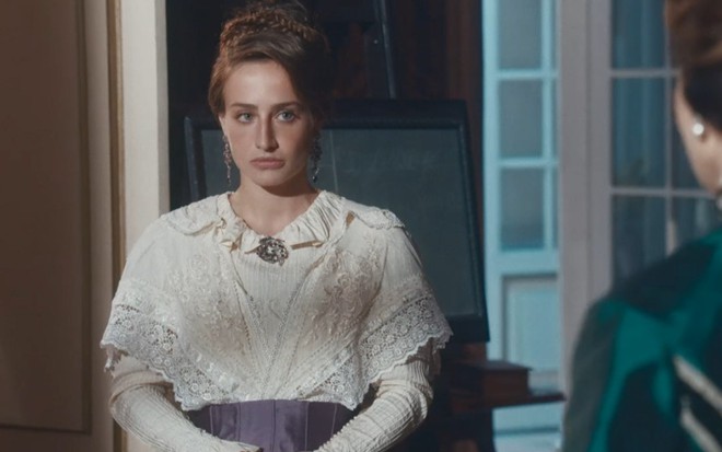 Bruna Griphao grava com cabelo preso, vestido rodado de época e expressão séria como Leopoldina de Nos Tempos do Imperador