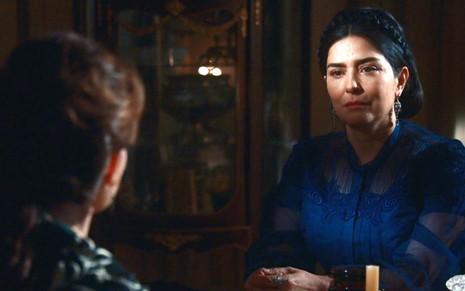 Teresa Cristina (Leticia Sabatella) está sentada no salão da Quinta em frente à Luísa em cena de Nos Tempos do Imperador