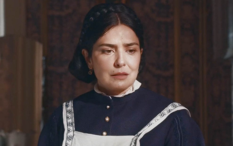 Teresa Cristina (Letícia Sabatella) está vestida de azul na sala da família imperial em cena de Nos Tempos do Imperador