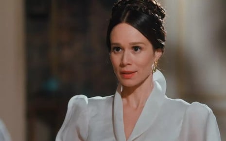 Mariana Ximenes grava com cabelo preso, vestido branco e expressão de empolgação como Luísa de Nos Tempos do Imperador