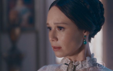 A atriz Mariana Ximenes, com expressão de tristeza, de perfil como a Luísa em cena de Nos Tempos do Imperador