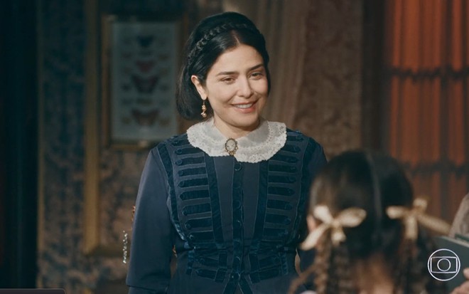 Leticia Sabatella grava com vestido azul e branco, cabelo preso e sorridente como Teresa Cristina de Nos Tempos do Imperador