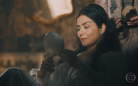 Leticia Sabatella grava cabisbaixa, com espelho na mão e vestido de época como Teresa Cristina de Nos Tempos do Imperador