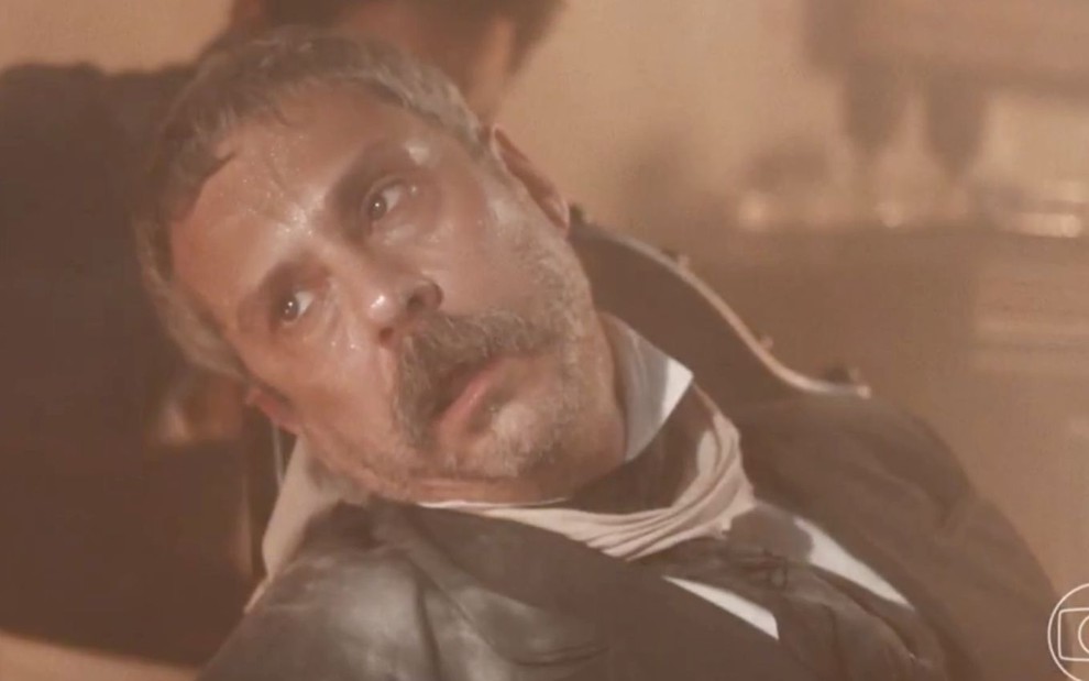 O ator Alexandre Nero com expressão desfalecida em meio a um incêndio como o Tonico em cena de Nos Tempos do Imperador
