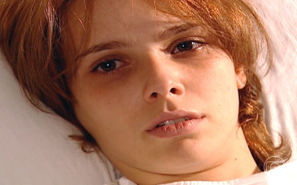 Débora Falabella grava cena deitada em cama de hospital, com aparência abatida, como Mel em O Clone