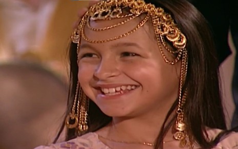 Carla Diaz em cena de O Clone: atriz está caracterizada como Khadija e sorri para alguém fora do quadro