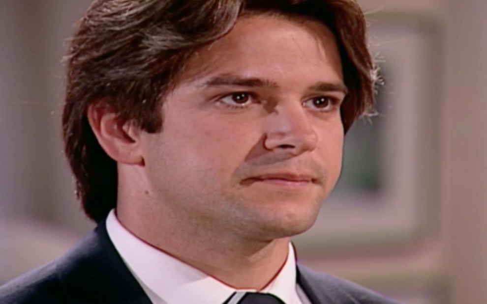 Murilo Benício caracterizado como Lucas em o Clone: ator está de terno e olha com desagrado para alguém fora do quadro