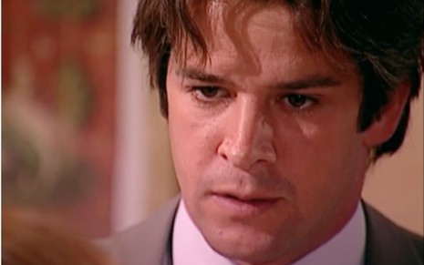 Murilo Benício caracterizado como Lucas em O Clone: ator está de terno e olha com desagrado para alguém fora do quadro