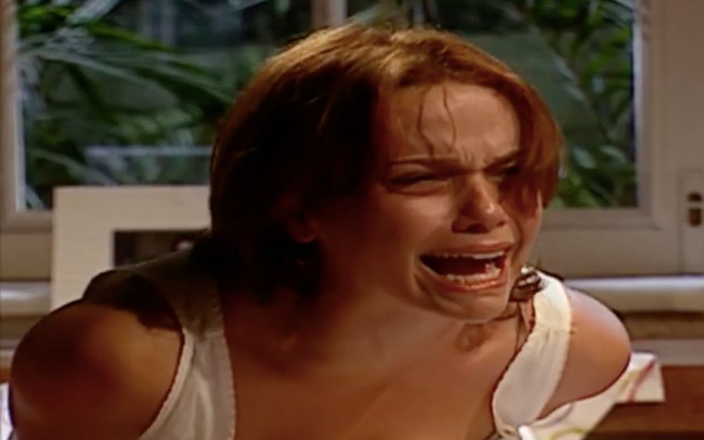 Débora Falabella em cena de O Clone: atriz usa regata branca, está sentada e grita para alguém fora do quadro
