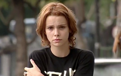 Débora Falabella em cena de O Clone: atriz está usando camiseta preta e está com os braços cruzados